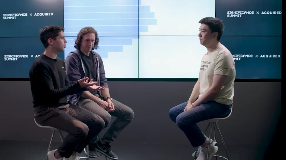Yuzheng Sun on stage with Ben Gilbert and David Rosenthal of Acquired at Significance Summit