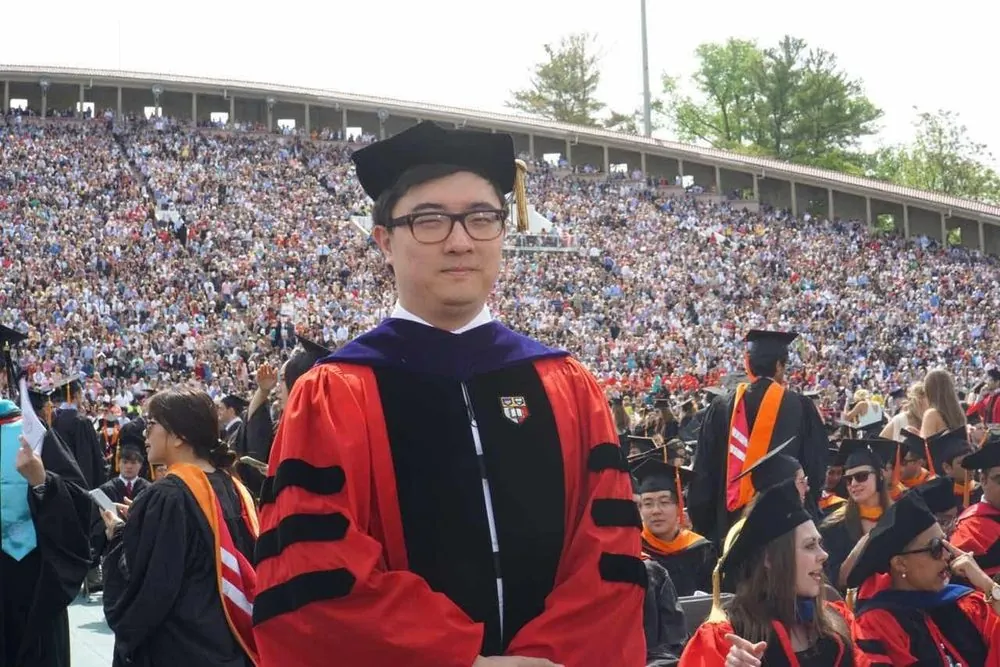 Yuzheng Sun in doctoral robes in the stadium at Cornell’s commencement